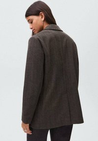 Blazer su misura marrone scuro con motivo a spina di pesce, rever a punta e taglio dritto. Progettato con una texture liscia e dettagli di cucitura sottili.