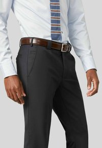 Op maat gemaakte donkergrijze broek met een gladde textuur, voorzien van zijzakken en een bruine leren riem met een zilveren gesp.