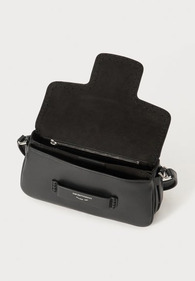 Svart läderhandväska med slät yta, präglad logga, dragkedjestängning och flätade detaljer på handtaget och locket. Inuti är väskan klädd i nubuck.