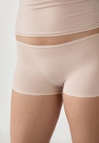 Boxer briefs beige realizzati in tessuto liscio ed elasticizzato, con una vestibilità aderente, un design semplice e una minima rifinitura lungo i bordi.