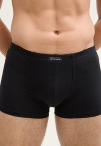Zwarte katoenen boxershorts met elastische tailleband, voorzien van een klein label aan de voorkant. Gladde textuur en aansluitend ontwerp.