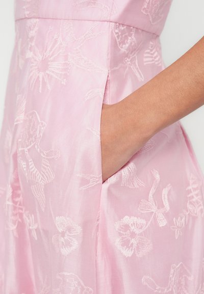 Robe rose ornée d'une broderie florale avec une texture lisse. Comprend un détail de poche latérale, mettant en avant des motifs cousus d'oiseaux et de fleurs.