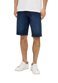 Shorts en denim bleu foncé avec une coupe droite, featuring des ourlets roulés. Associés à des baskets blanches. Le tissu semble lisse avec un léger dégradé.