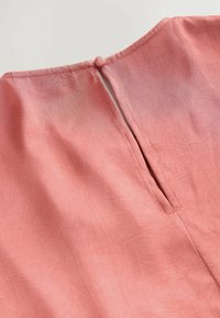 Różowa sukienka z malinowym odcieniem, z tyłu zapinana na okrągły guzik, z pionowym rozcięciem, teksturowanym materiałem i widocznymi detalami szwów.