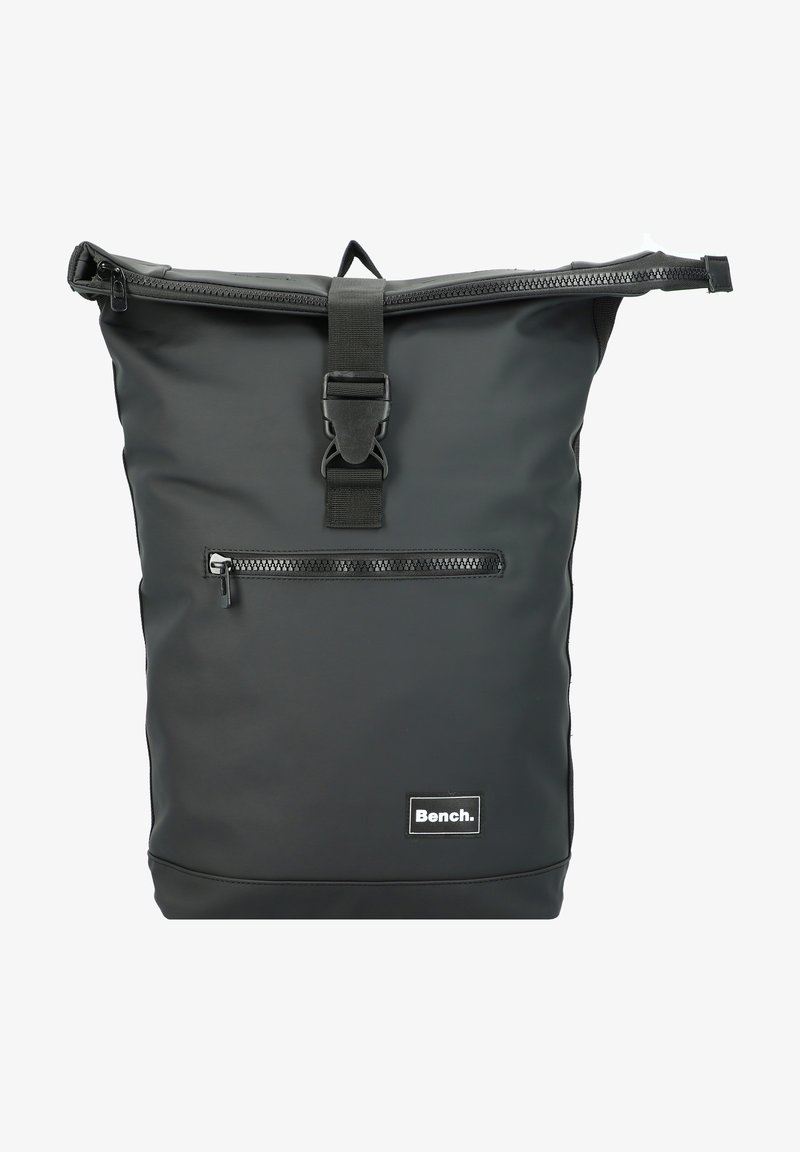 Mochila negra impermeable con cierre enrollable, bolsillo frontal con cremallera, correa de hombro ajustable y etiqueta con el logo de Bench en la parte inferior. Textura suave.