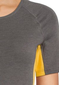 Maglietta grigia a maniche corte con un pannello laterale giallo testurizzato, caratterizzata da un collo rotondo e dettagli di cucitura visibili.