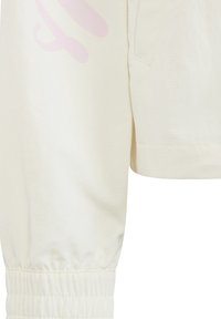 Světlý krémový pulovr s dlouhými rukávy, žebrovanými manžetami a velkým růžovým potiskem na přední straně. Vyrobeno z měkké bavlněné tkaniny.