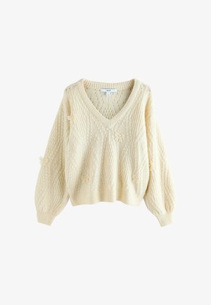 Pull en maille torsadée crème avec un col en V, des manches bouffantes et de délicats accents floraux. Ourlet côtelé et motifs texturés sur l'ensemble.