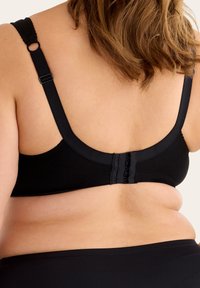 Svart bh med breda axelremmar, slät textur och hyskokslås. Designen har en sömlös look på baksidan.