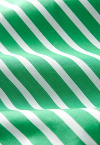 Zielony materiał z równomiernie rozmieszczonymi białymi skośnymi paskami, ukazujący gładką, lekko falistą strukturę oraz drobne detale splotu.