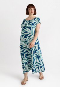 Maxiklänning med ett blått och vitt bladmönster, med volangkant vid halsen och korta ärmar, tillverkad av lätt material.