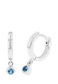 Aros de plata con un acabado suave, que presentan piedras preciosas azules colgantes. El diseño es redondeado con un mecanismo de cierre seguro.