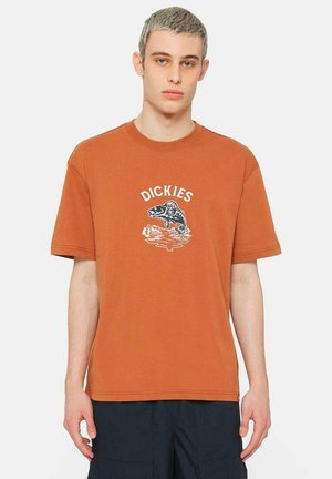 Camiseta de algodón naranja con mangas cortas y cuello redondo. Presenta un gráfico de un pez y la palabra "DICKIES" en blanco encima del diseño.