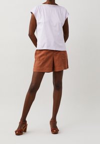 Světle fialové bavlněné tričko s krátkými rukávy a krajkovým detailem na výstřihu, doplněné o šortky v barvě rezavé s kapsami.