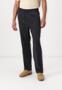 Schwarze, leichte Jogginghose mit elastischem Taillenbund und verstellbarem Kordelzug. Verfügt über Seitentaschen und einen entspannten Schnitt.