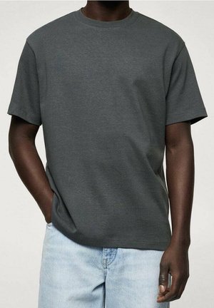 Camiseta de algodón gris oscuro con mangas cortas y cuello redondo, combinada con jeans de mezclilla azul claro. Diseño simple y sin adornos.