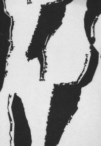 Black and white fabric featuring a bold abstract pattern with distinct, irregular shapes and visible texture. Soft, woven material.