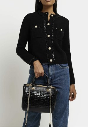 Cardigan en laine noire avec accents pailletés et boutons en perles, assorti à un sac à main en cuir verni noir avec motif embossé et chaîne argentée.