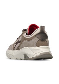 Zapatilla gris y beige con materiales de ante y tela. Presenta una suela blanca, un tacón grueso y un forro interior rojo. Incluye el logo en el talón.
