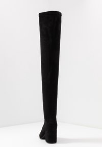 Schwarze Overknee-Stiefel aus weichem Stoff, mit einem stabilen Absatz und einer glatten Textur, in einer taillierten Silhouette und minimalistischem Design.