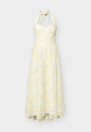 Κίτρινο και λευκό φόρεμα με λαιμόκοψη halter και μοτίβο από δαντέλα στρογγυλών τρυπών, με δομημένο μπούστο, ρέει μέχρι το μέσο της γάμπας με ελαφρώς ασύμμετρο τελείωμα.