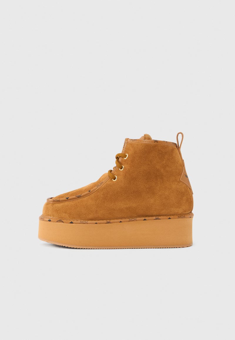 Bottes cheville en daim marron clair avec une semelle compensée. Elles présentent un bout arrondi, un laçage à l'avant et des détails de marque le long de la semelle.
