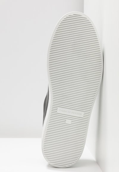 Sneaker nera con suola in gomma testurizzata, dotata di scanalature orizzontali per una migliore aderenza. Il logo "Tiger of Sweden" è visibile sul lato della suola.