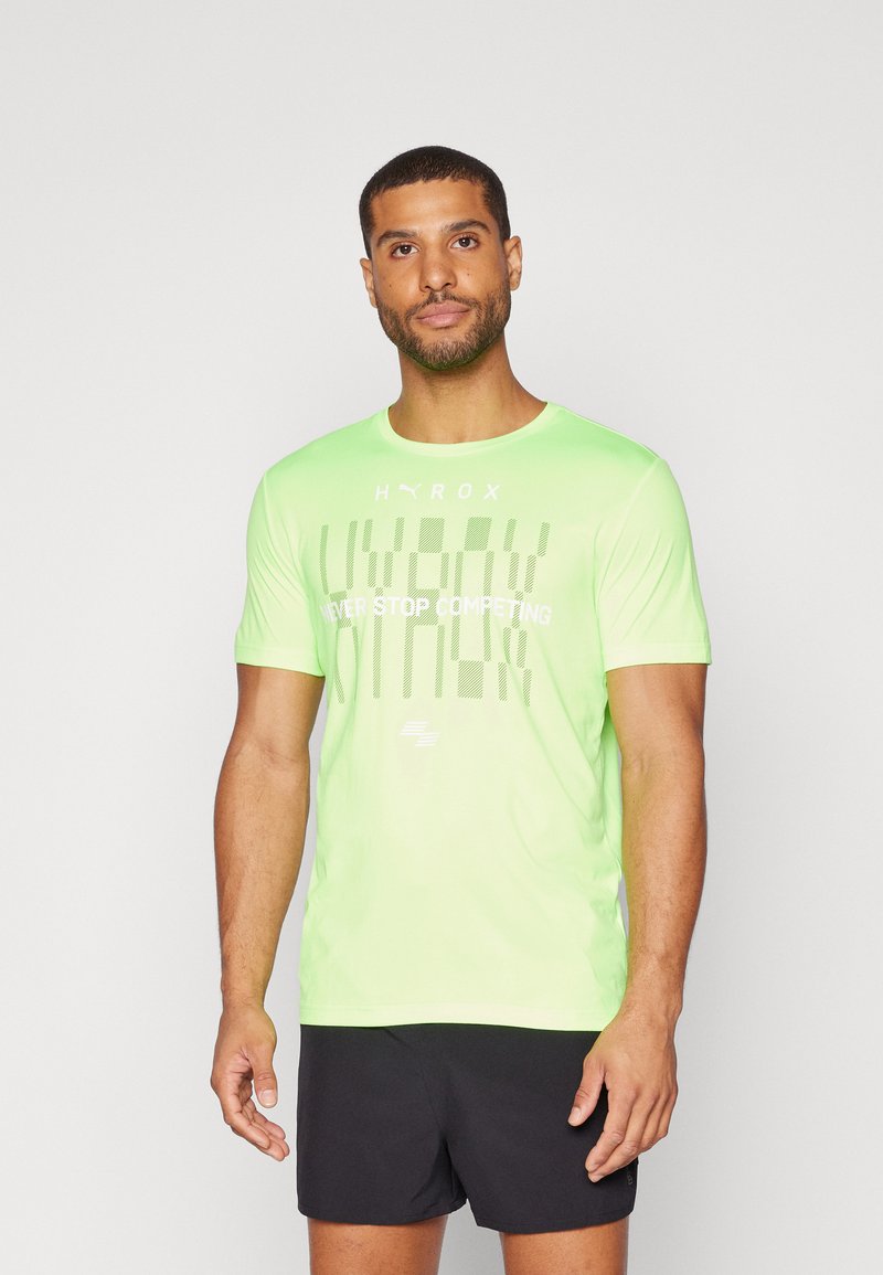 Camiseta deportiva de color verde neón con cuello redondo, mangas cortas y un diseño de texto audaz y contrastante en el frente. Shorts negros debajo.