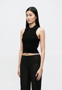 Fekete bordás crop top galléros, gombos záródással, áttetsző fekete csíkos nadrággal párosítva. Sima textúra, modern fazon.