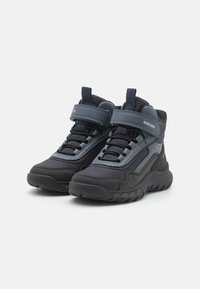 Zapatillas altas Geox en materiales negro y azul marino oscuro. Cuentan con un collarín acolchado, una cinta de Velcro y una suela de goma texturizada para mayor tracción.