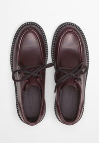 Burgunderfarbene Leder Schuhe mit runder Zehenform, Schnürsenkeln und Gummisohle. Mit gesteppten Akzenten und einer strukturierten Außensohle für besseren Halt.
