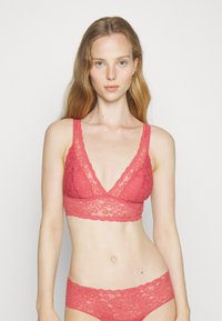 Bralette de renda coral com alças largas e decote em V profundo, combinado com calcinhas de renda correspondentes com borda em Format de onda.