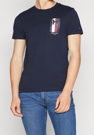 Granatowy bawełniany t-shirt z nadrukiem w kolorach czerwonym, białym i niebieskim. Krótkie rękawy i okrągły dekolt.