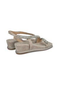 Beige suède sandalen met een metallic zilveren zool, voorzien van kruislings gespen versierd met kleine strasssteentjes en een gevoerde inlegzool.