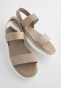 Beige nubukist sandaalid, millel on kaks laia rihma; tekstuuriga aksessuaaririhm; valge tald, millel on kudumisest jute detailid; minimalismi stiilis, avatud disain.