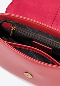 Interno di una borsa a tracolla rossa in pelle con un compartimento con zip e molteplici tasche. Morbida texture in suede con una chiusura a scatto in metallo dorato.