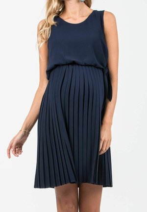 Mørkeblå, ærmeløs plisseret kjole med afslappet pasform, der har en bindedetalje i taljen og et tekstureret stof, som fremhæver bevægelse.