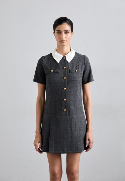 Robe à carreaux gris avec des manches courtes, un col blanc, des détails en boutons dorés, et un ourlet plissé. Coupe ajustée ; tissu texturé.