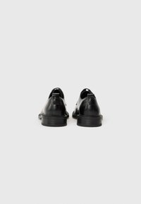 Black leather shoes with a smooth finish, rounded toe, low stacked heel, and reinforced pull-tabs on the back.