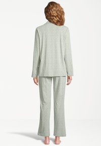 Vihreä pilkullinen pyjama-asusetti pehmeästä kankaasta, jossa on pitkähihaisuus paita kauluksella ja vastaavat leveälahkeiset housut.