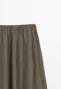 Jupe en tissu froissé vert olive avec une ceinture élastique, présentée sur un fond blanc uni.
