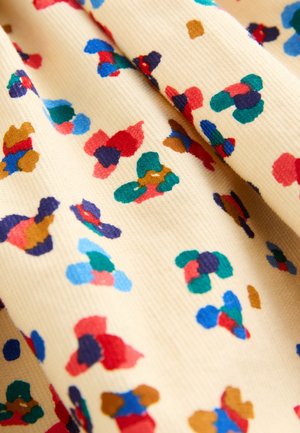 Keltainen puuvillakangas, jossa on teksturoitu pinta ja abstrakteja monivärisiä kuvioita punaisena, sinisenä, vihreänä ja ruskeana.