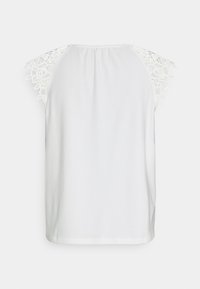 Blouse blanche sans manches avec des manches courtes en dentelle florale et un col froncé, vue de dos sur un fond uni.