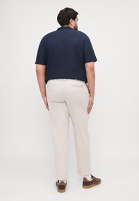 Navy blue short-sleeve shirt with vertical stripes, paired with beige trousers. The shirt features a classic collar and the trousers have side pockets.