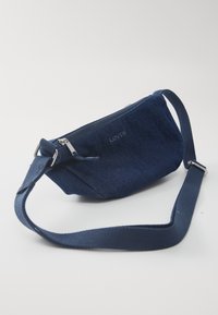 Mörkblå denim midjeväska med dragkedjestängning, justerbar rem och en slät yta. Har Levi's-logotypen präglad på framsidan.