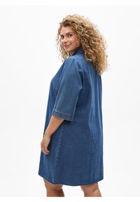 Farkkumekko, jossa on lyhyet hihat, väljä istuvuus ja napitettavat kaulukset. Mekossa on polven yläpuolelle ulottuva pituus ja pehmeä, teksturoitu sininen kangas.