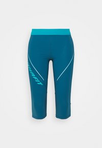 Tyrkysové sportovní capri kalhoty se širokým pasem, které mají kontrastní aqua logo a diagonální bílé akcenty po stranách. Hladká, elastická tkanina.