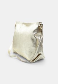 Metallic guld skuldertaske med en tekstureret overflade, der har en enkel rem og et rummeligt indre. Blød, slasket kropsform.