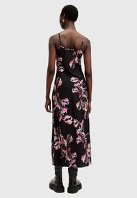 Svart blommig maxiklänning med tunna axelremmar, med stora rosa och vita blommönster, slät textur och en luftig design. Svarta combat boots bärs.