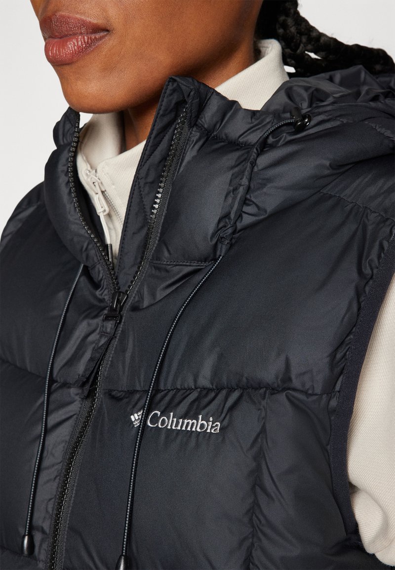 Czarna kamizelka z kapturem, wykonana z pikowanej tkaniny i zapinana na zamek. Na przodzie haftowane logo Columbia. Gładka tekstura z regulowanymi sznurkami.